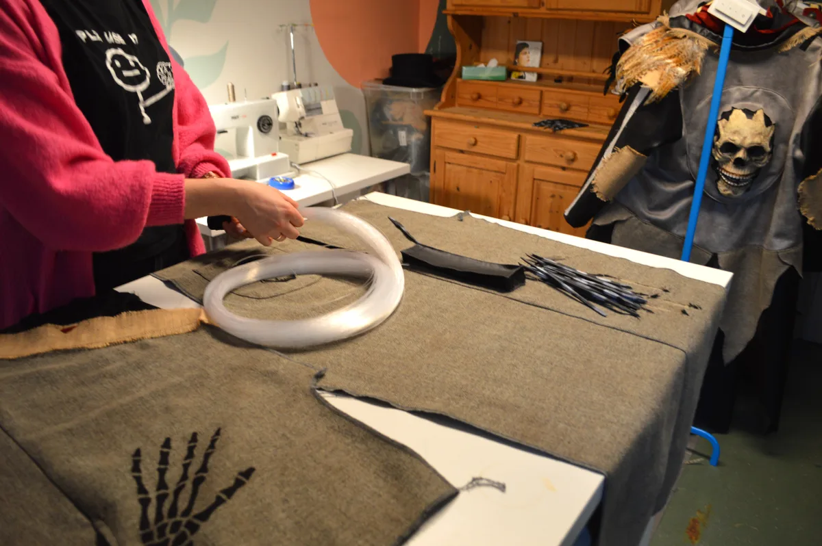 Die Modedesignerin hält eine Lichterkette in der Hand.
